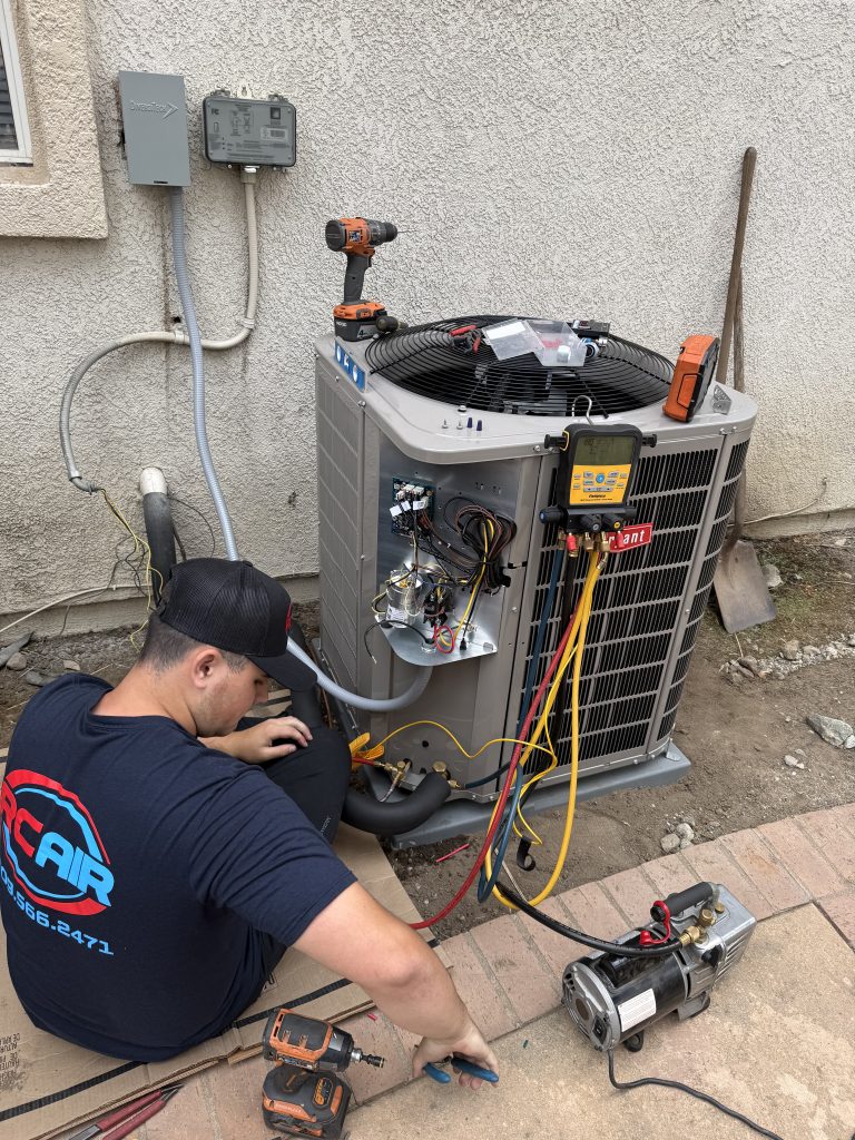 An RC Air tech sitting alongside an outdoor AC unit, running some tests.